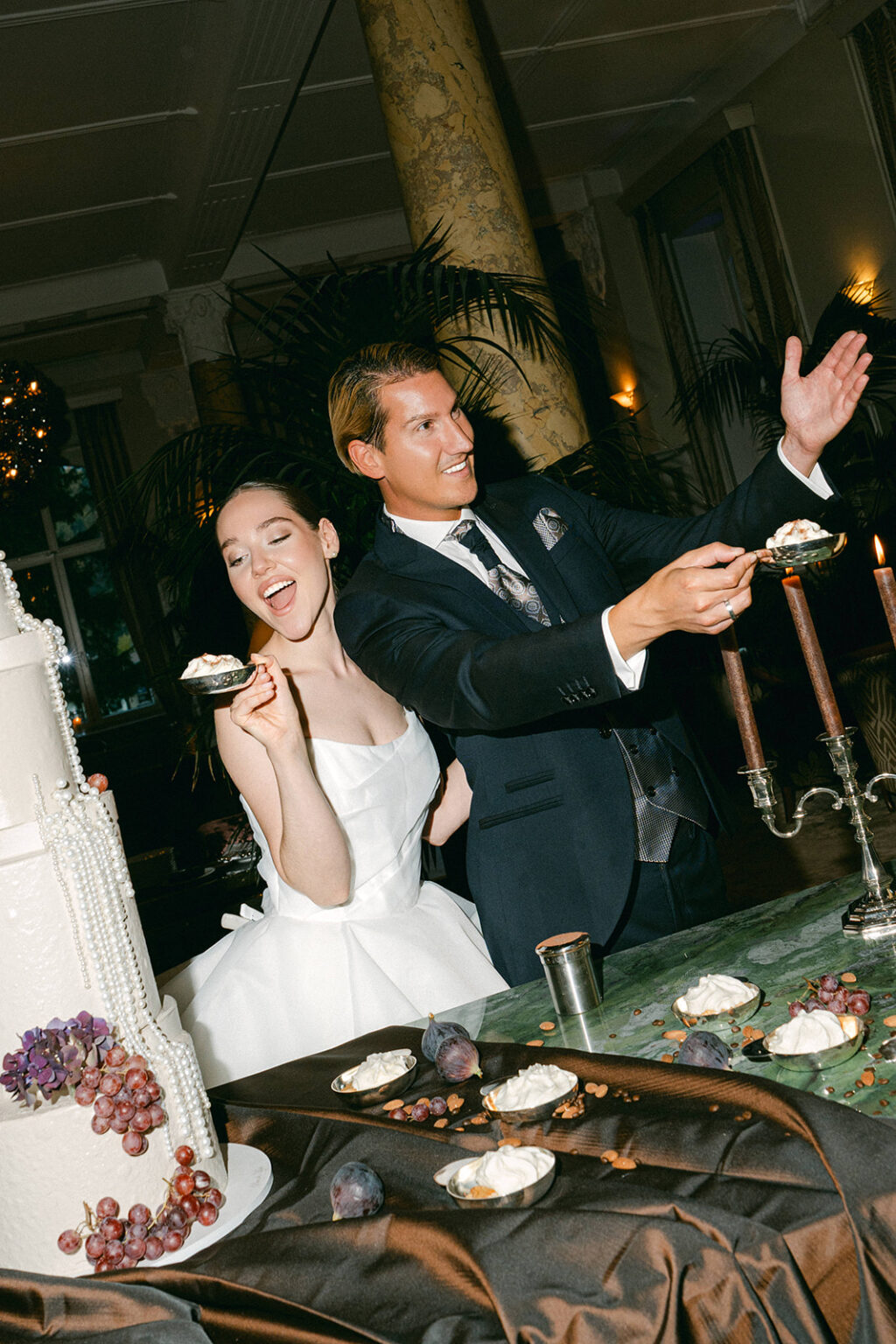 A happy bride and groom laugh while serving cake together at their wedding celebration in Switzerland, creating unforgettable memories surrounded by their loved ones.