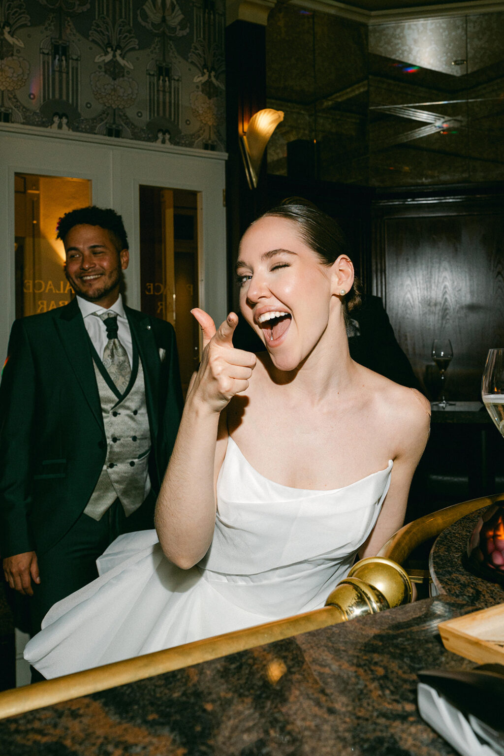 A wedding singer in a white dress winks and gestures playfully at the camera; a man in a suit smiles behind her - festive atmosphere in Zurich, Switzerland.