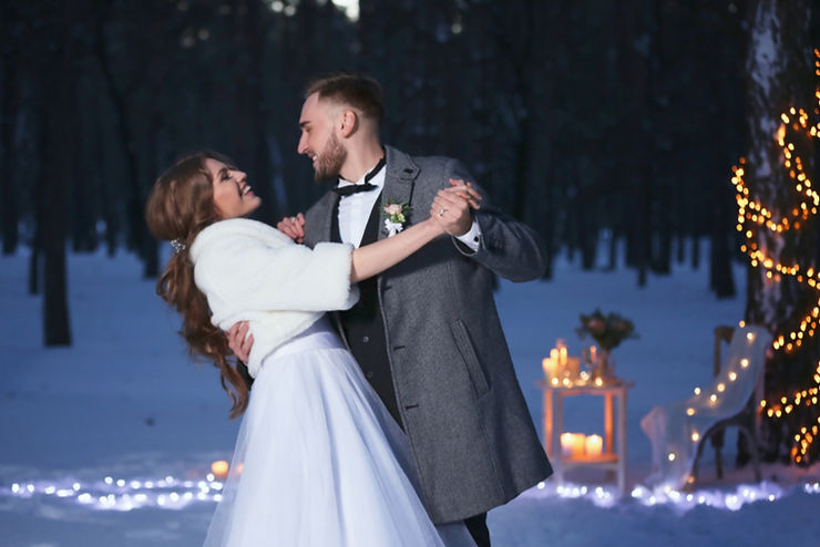 Ein Brautpaar tanzt im Freien im Schnee, umgeben von Lichtern und Kerzen, während eine Hochzeitssängerin aus Zürich romantische Melodien erklingen lässt.
