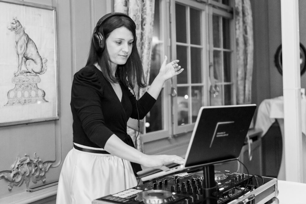 Naomi Ben mit Kopfhörern mischt Musik an einem Controller in einem stilvollen Züricher Raum mit großen Fenstern und gerahmter Kunst.