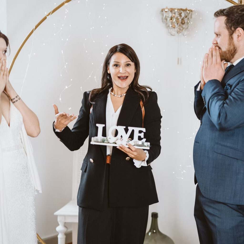 Hochzeitssängerin Naomi Ben mit einem LOVE-Schild steht zwischen dem freudig überraschten Brautpaar und fängt einen zauberhaften Zürcher Hochzeitsmoment ein.